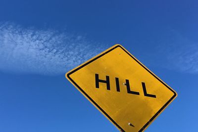 Low angle view of road sign against blue sky