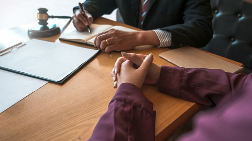 Lawyer talking to female while sitting by table in office