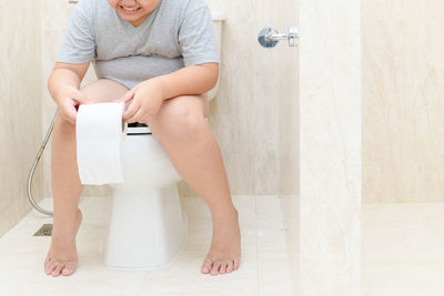 Low section of boy sitting in toilet