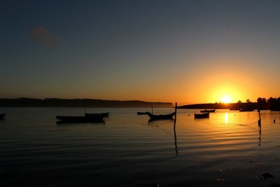 Silhouette boats in lake against sky during sunset