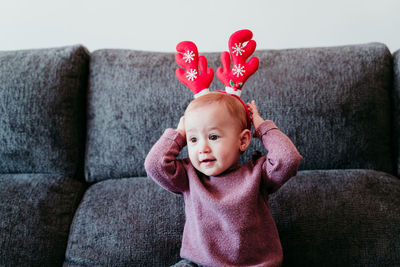 Cute smiling baby girl sitting on sofa at home