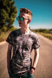 Young man standing on road against sky