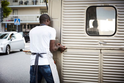 Male owner unlocking door of food truck on city street