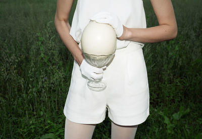 Midsection of woman holding umbrella while standing on field