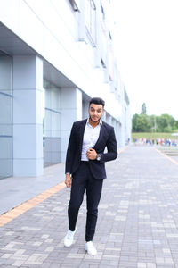 Young businessman standing against building