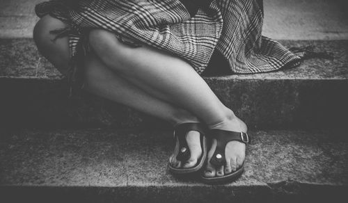 Low section of woman in high heels sitting outdoors