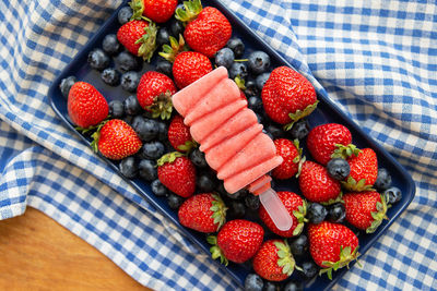 Fresh strawberry and blueberry ice cream lay on fresh strawberry and blueberry.