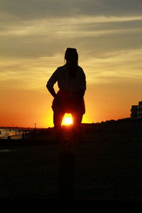 Silhouette man standing on field against sky during sunset