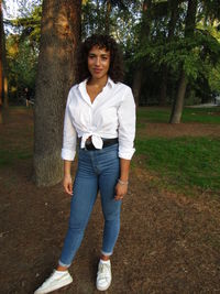 Portrait of teenage girl standing on tree trunk