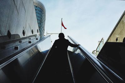 Low angle view of person on escalator against sky