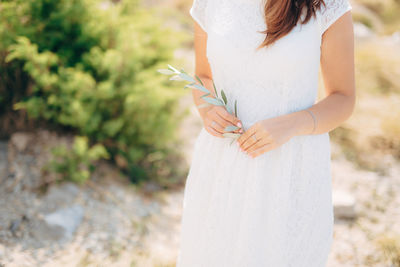 Midsection of woman holding white while standing outdoors