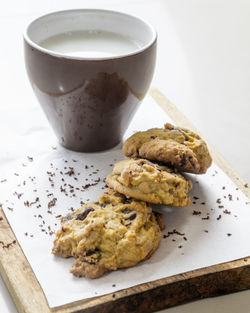 Close-up of cookies and milk in mug on cutting board