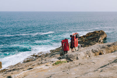 People with mattress walking at beach against sky