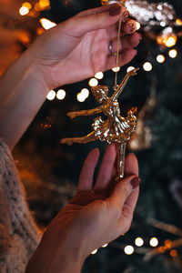Female hands holding a golden christmas toy figurine of a ballerina. magic winter details 