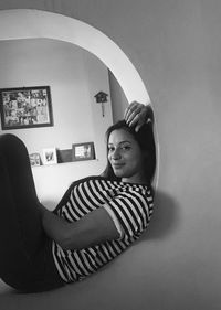 Portrait of smiling woman sitting against wall at home