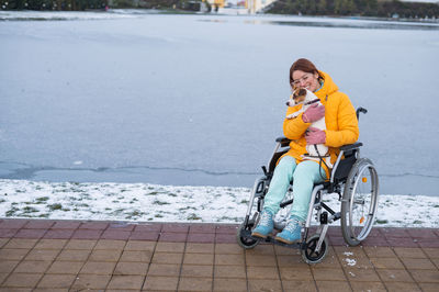 Side view of young woman sitting on snow