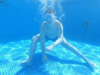 Young man enjoying underwater in swimming pool