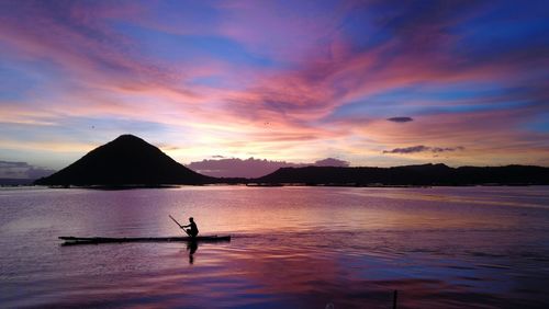 Silhouette person in sea against sky during sunset