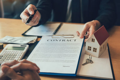 Midsection of man holding paper with text on table