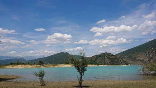 Scenic view of lake by mountains against sky