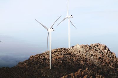 Low angle view of windmills on mountain against sky