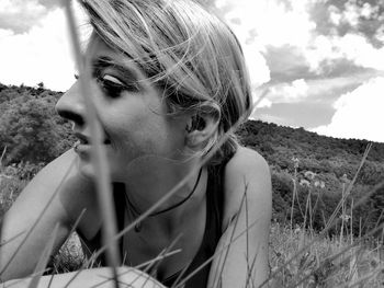 Close-up of young woman in field against sky