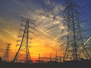 Low angle view of electricity pylon against sky during sunset