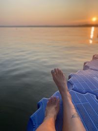 Low section of woman relaxing in sea against sky