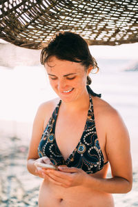 Young woman looking away while standing on beach