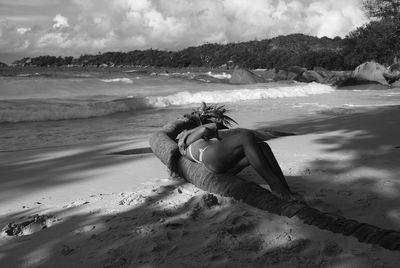 Woman resting in fallen palm tree at beach