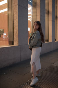 Full length of young woman standing against built structure