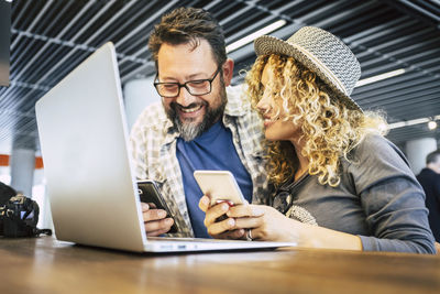 Smiling friends using phone while sitting on table