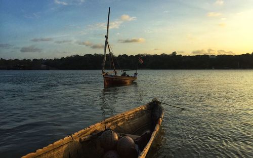 Fishing boat in sea against sky during sunset