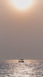 Silhouette boat sailing in sea against sky during sunset