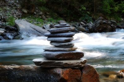 Stack of stones by flowing river in forest