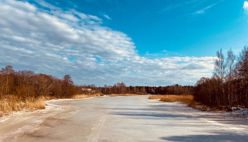 Road amidst trees against sky during winter