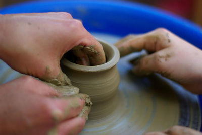 Cropped hands of people making clay pot