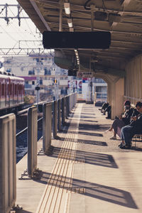 Rear view of people sitting on railway station platform