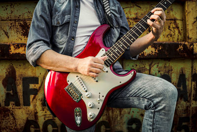 Midsection of man playing guitar