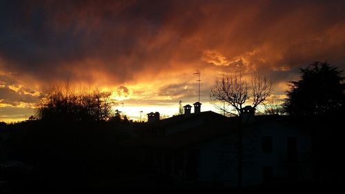 Silhouette trees and buildings against sky during sunset