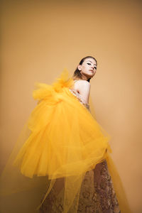 Portrait of a smiling young woman against yellow background