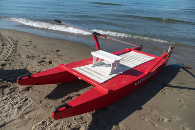 Red rescue boat moored on shore at beach