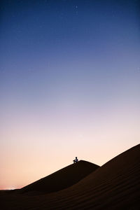 Silhouette person against clear sky at night