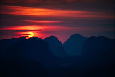 Scenic view of silhouette mountains against orange sky