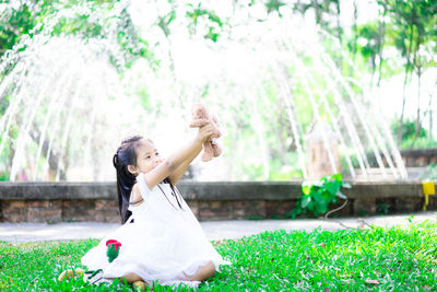 Woman with arms raised while standing against plants