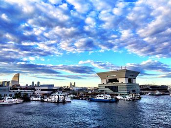Boats in river against cloudy sky