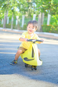 Full length of cute boy on yellow while sitting outdoors