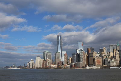 Sea by modern buildings against sky in city