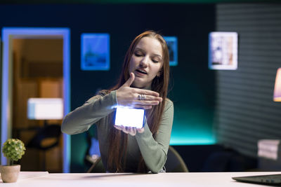 Young woman using mobile phone while sitting at table