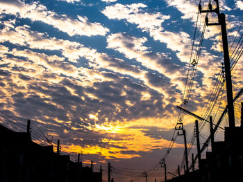 Low angle view of silhouette electricity pylon against sky during sunset